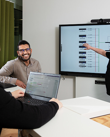 Three IT experts in a meeting room.