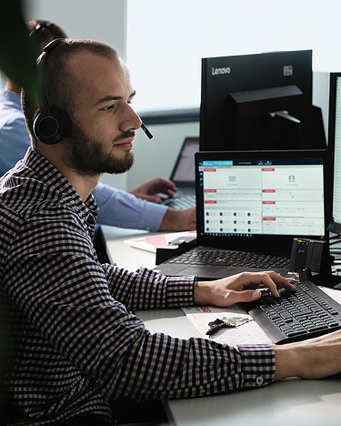 A young man with a headset works on a screen.