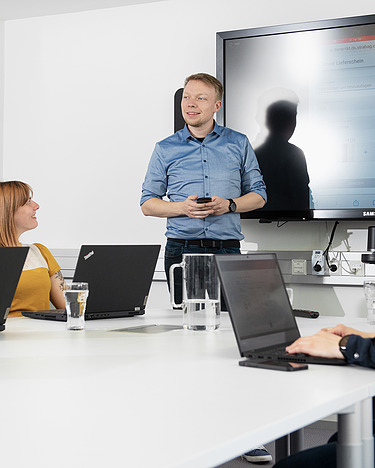 A young man gives a presentation to his team in a meeting room.